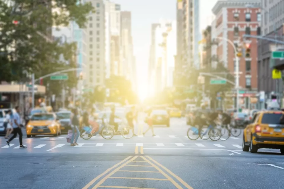 Busy crosswalk with people and bikes in New York City on a bright afternoon.